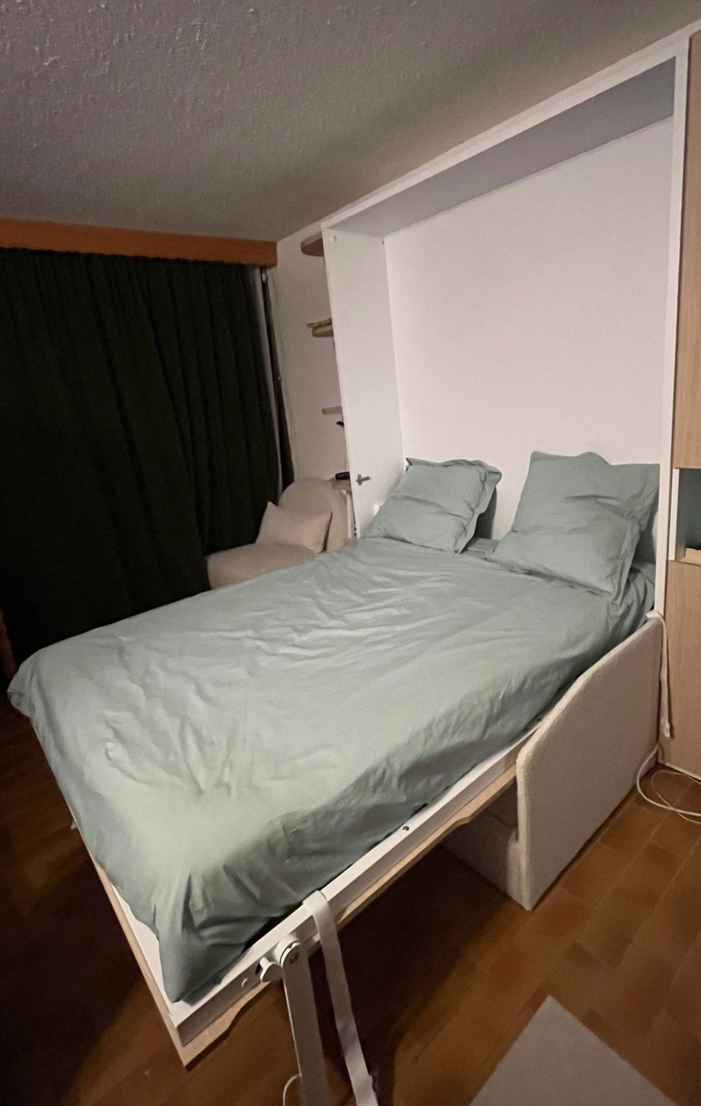 Le lit escamotable 140 × 190 ouvert, avec couette et oreillers